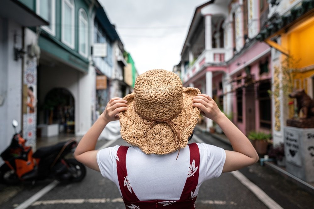 ที่เที่ยวภูเก็ต ท่องเที่ยวภูเก็ต ไม่ใช่ทะเล หญิงสาวชาวจีน สวมหมวก ยินท่ามกลางตึกโบราณ