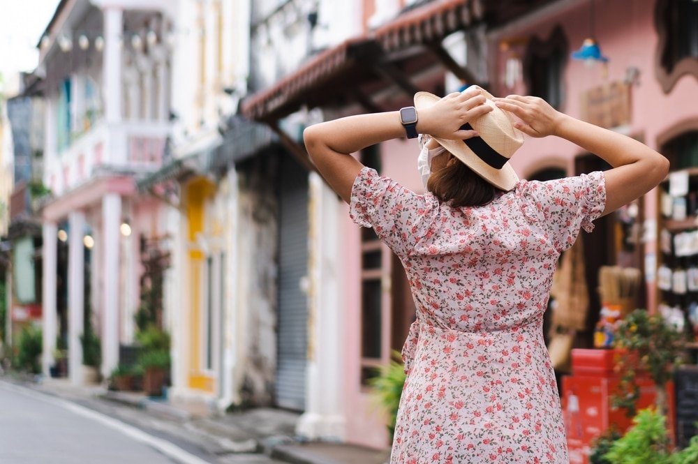 a woman wearing a ที่เที่ยวภูเก็ตไม่ใช่ทะเล hat and a face mask