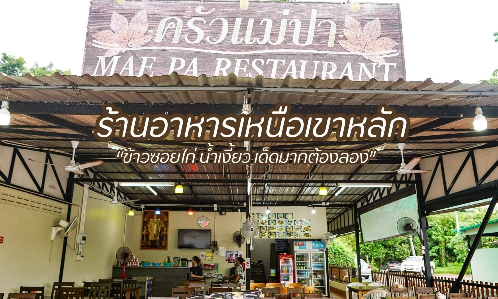 วิวกลางแจ้งของร้านอาหารแม่ปาพร้อมป้ายไม้ต้อนรับพร้อมข้อความทั้งภาษาไทยและภาษาอังกฤษ พื้นที่นั่งเล่นกว้างขวางที่รายล้อมไปด้วยแมกไม้เขียวขจี ขอเชิญคุณมาเพลิดเพลินกับข้าวขาเพลินพุงอันโด่งดัง