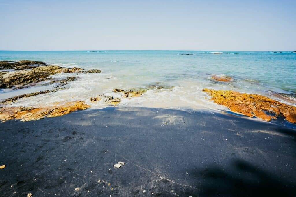 หาดทรายสีดำที่มีแนวหินทอดยาวไปจนถึงทะเลสีฟ้าครามอันเงียบสงบภายใต้ท้องฟ้าที่แจ่มใส เป็นตัวอย่างที่ชัดเจนของความงามอันเงียบสงบของ ที่เที่ยวพังงา