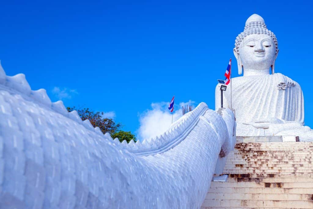      วัดพระใหญ่ภูเก็ต    พระพุทธมิ่งมงคลเอกนาคคีรี พระพุทธรูปสีขาวขนาดใหญ่ ประทับอยู่บนขั้นบันไดต่างๆ ใต้ท้องฟ้าสีครามสดใส ธงบนเสาช่วยเพิ่มสีสันให้กับบรรยากาศอันเงียบสงบของวัดพระใหญ่ภูเก็ต