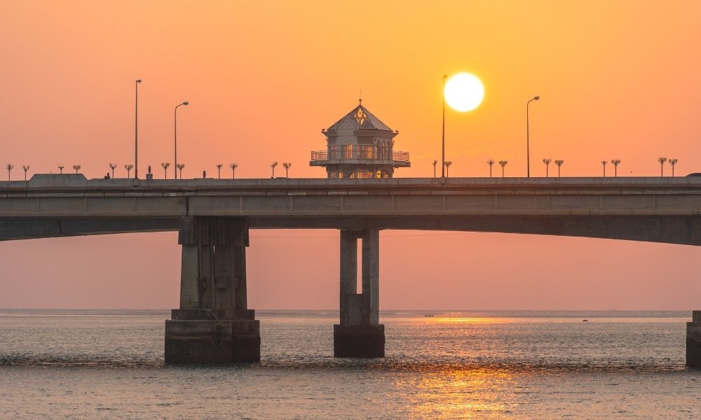 สะพานที่มีอาคารเล็กๆ อยู่ด้านบน มีเงาตัดกับท้องฟ้ายามพระอาทิตย์ตกเหนือน้ำอันสงบ ชวนให้นึกถึงสะพานรักสารสินอันเป็นสัญลักษณ์