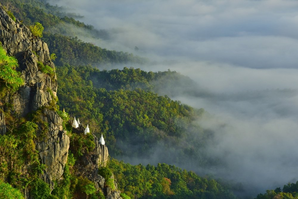 สถานที่ท่องเที่ยวไทย ที่สวยงามแห่งนี้ตั้งอยู่ท่ามกลางภูมิประเทศของภูเขา มีป่าไม้เขียวขจีหนาแน่นและวัดสีขาวตั้งอยู่บนหน้าผา บางส่วนถูกปกคลุมไปด้วยหมอกและเมฆ เหมาะสำหรับผู้ที่ต้องการท่องเที่ยวไทยพร้อมชมทิวทัศน์ที่สวยงามตระการตา