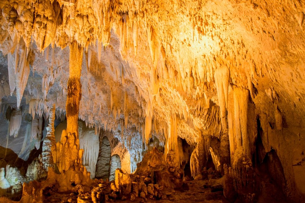 หินงอกหินย้อยในถ้ำที่มีแสงสลัวๆ ด้วยเฉดสีทองและสีส้มสร้างบรรยากาศที่น่าหลงใหล ทำให้ที่นี่เป็นจุดหมายปลาย ท่องเที่ยวตรัง ทางที่ต้องไปชมสำหรับผู้สำรวจท่องเที่ยวอีสาน.