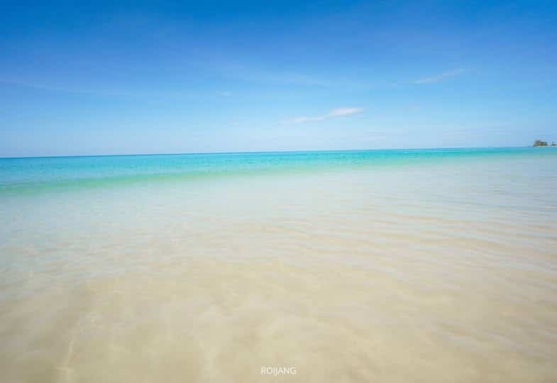 ค้นพบบรรยากาศชายหาดอันเงียบสงบที่เที่ยวเขาหลัก ซึ่งมีน้ำตื้นที่ใสสะอาดทอดยาวไปจนถึงเส้นขอบฟ้าสีฟ้าครามภายใต้ท้องฟ้าสีครามสดใส.