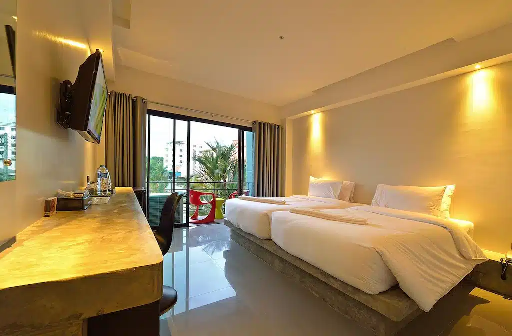  ที่พักกระบี่ ห้องพักโรงแรมทันสมัยที่โรงแรมกระบี่มีเตียงเดี่ยว 2 เตียง ทีวีติดผนัง โต๊ะกว้างขวางพร้อมเก้าอี้ และระเบียงพร้อมที่นั่งกลางแจ้งที่มองเห็นได้ผ่านประตูกระจกบานเลื่อน เหมาะสำหรับที่พักในกระบี่ครั้งต่อไปของคุณ.