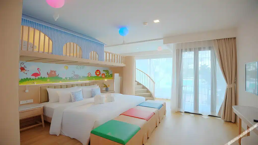 ห้องนอนสำหรับครอบครัวที่มีแสง ที่พักอ่าวนาง สว่างสดใสที่อ่าวนางราคาถูกพร้อมเตียงขนาดใหญ่ ภาพจิตรกรรมฝาผนังรูปสัตว์สีสันสดใส พื้นที่เล่นใต้หลังคา บันไดเวียน เก้าอี้สตูลเนื้อนุ่ม และเฟอร์นิเจอร์ทันสมัย พร้อมหน้าต่างสูงจากพื้นจรดเพดานพร้อมผ้าม่านโปร่ง.