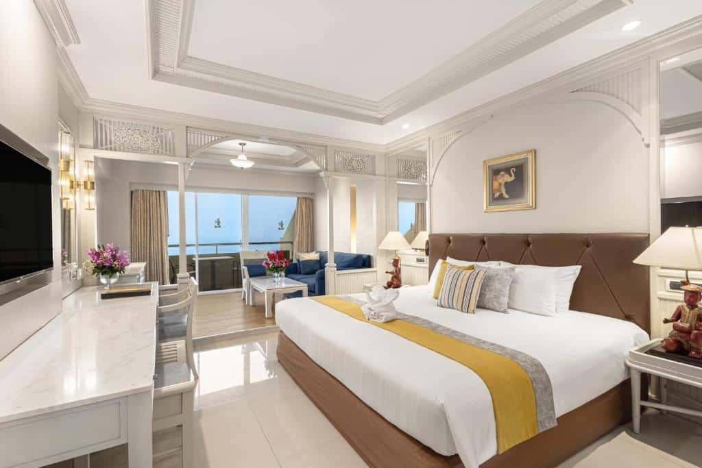 ห้องพักในโรงแรมกว้างขวางพร้อมเตียงขนาดใหญ่ โต๊ะทำงาน ทีวีจอแบน และพื้นที่นั่งเล่น มองเห็นวิว ที่เที่ยวพัทยา ทะเล เหมาะสำหรับผู้ที่มองหาเที่ยวพัทยาหรือสำรวจที่เที่ยวพัทยาติดทะเล การตกแต่งที่เป็นกลางเน้นสีเหลืองสดใส.