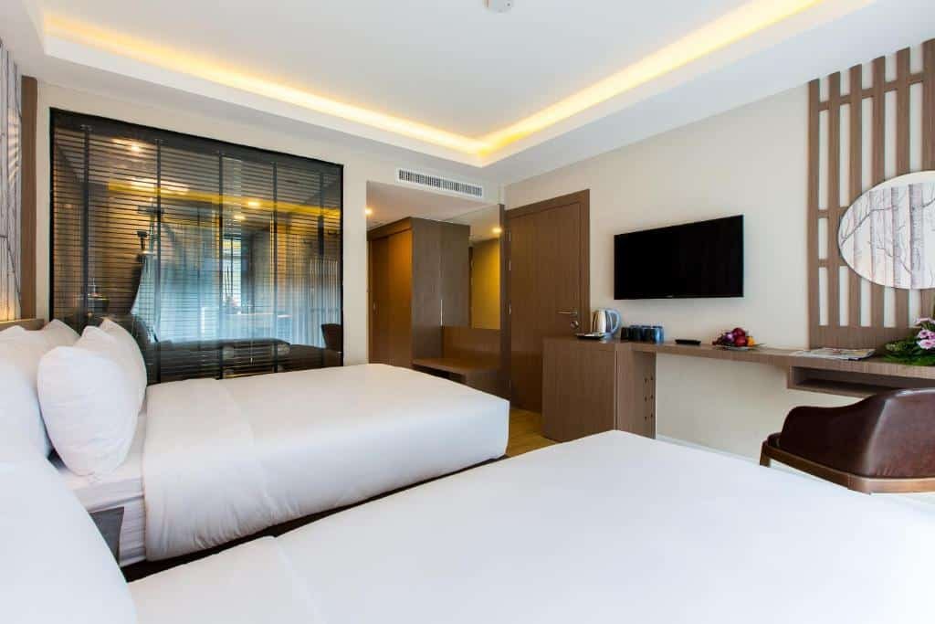 ห้องพักโรงแรมทันสมัยที่โรงแรมกระบี่พร้อมเตียงคู่ 2 เตียง ทีวีติดผนัง โต๊ะและเก้าอี้ ห้องน้ำผนังกระจก และการตกแต่งในโทนสีกลาง เหมาะสำหรับการพักผ่อน ที่พักกระบี่ ในกระบี่ครั้งต่อไปของคุณ.