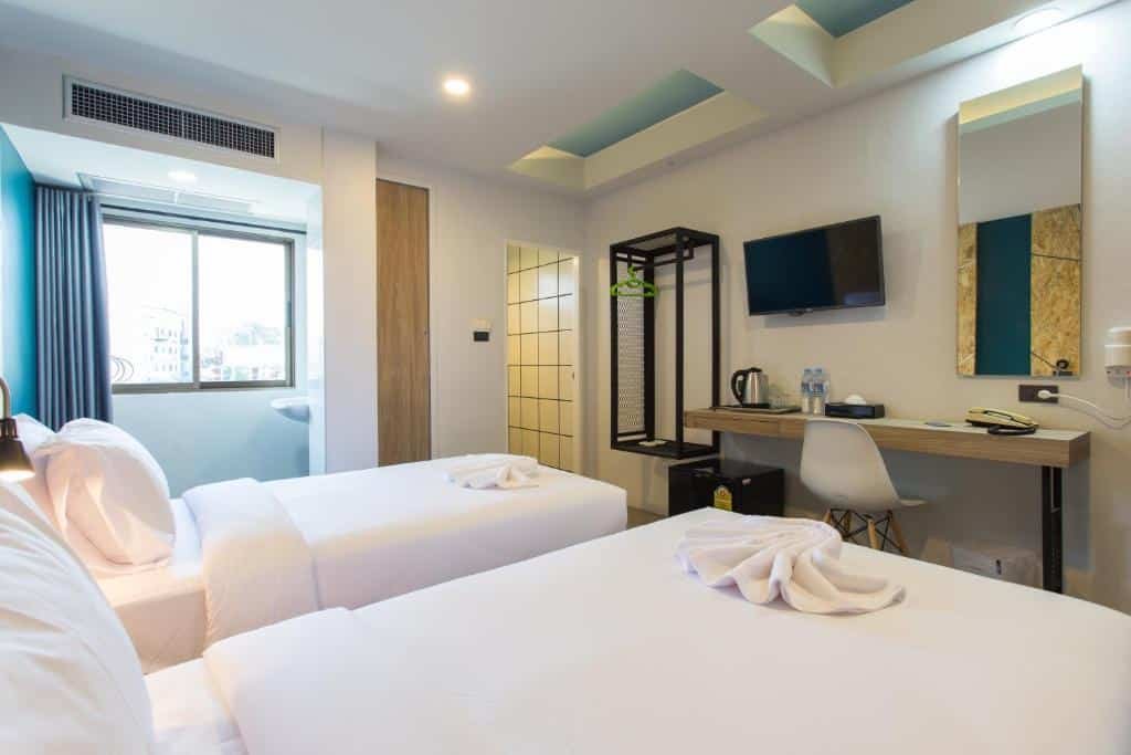 ห้องพักโรงแรมทันสมัยที่ โรงแรมกระบี่ พร้อมเตียงเดี่ยว 2 เตียง โต๊ะทำงานพร้อมกาต้มน้ำและขวดน้ำ ทีวีติดผนัง ตู้เสื้อผ้า และหน้าต่างที่เปิดรับแสงธรรมชาติ เหมาะสำหรับประสบการณ์การเข้าพักครั้งต่อไปของคุณ.