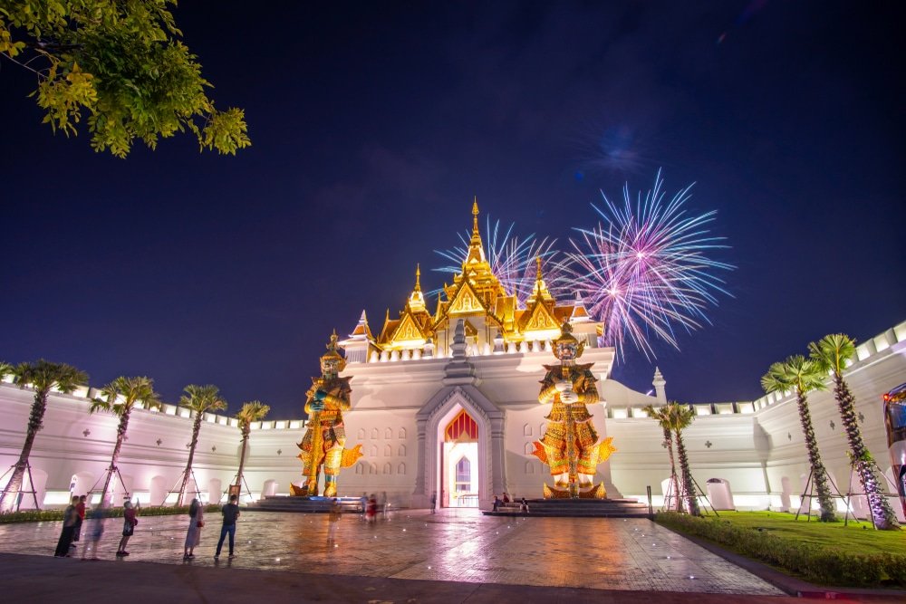 วัดที่สว่างไสวพร้อมหลังคาหรูหราและรูปปั้นผู้พิทักษ์ขนาดใหญ่ตั้งตระหง่านอยู่ใต้ท้องฟ้ายามค่ำคืนพร้อมดอกไม้ไฟหลากสีสันที่ระเบิดเหนือศีรษะ ทำให้ที่นี่เป็นสถานที่ที่ต้องไปชม ที่เที่ยวพัทยา โดยไม่ต้องมาเที่ยวพัทยาเป็นพิเศษ.