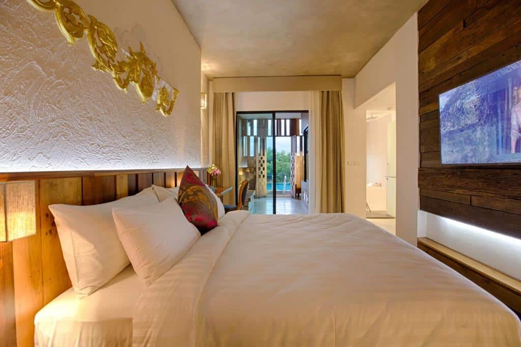 ห้องพักโรงแรมสมัยใหม่พร้อมเตียงคู่ที่จัดแต่งอย่างเรียบร้อย, ศิลปะ ที่พักกาญจนบุรี ตกแต่งผนัง, ไม้ตกแต่ง, และวิวของระเบียงหรือเฉลียงผ่านประตูกระจก—เหมาะสำหรับการพักผ่อนที่ผ่อนคลายที่ ที่พักกาญจนบุรีริมน้ำ.