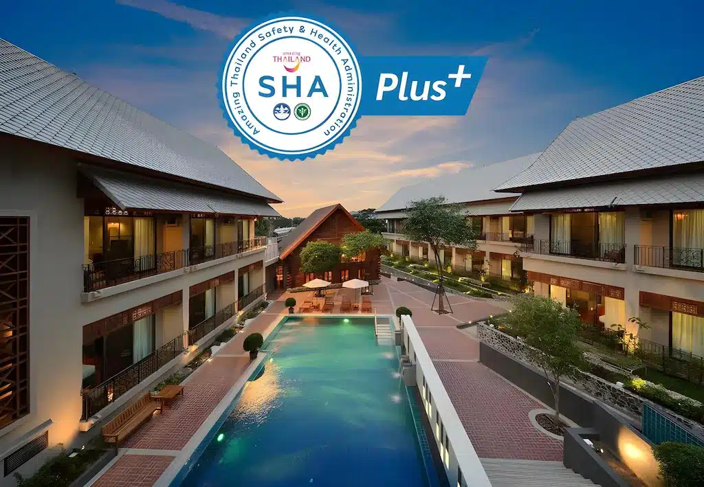 ลานโรงแรมสมัยใหม่พร้อมสระว่ายน้ำกลางแจ้งในยามเย็น พร้อมสัญลักษณ์รับรองความปลอดภัยและสุขภาพ  ที่พักกาญจนบุรี "SHA Plus+" — เหมาะสำหรับผู้ที่ต้องการที่พักกาญจนบุรี หรือ รีสอร์ทกาญจนบุรี สำหรับการพักผ่อนอย่างผ่อนคลาย.