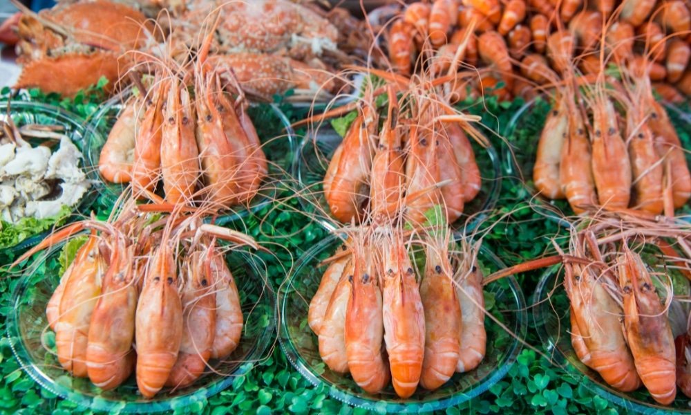 จานกุ้งสดวางบนผักชีสีเขียวที่ตลาด ที่เที่ยวใกล้กรุงเทพ อาหารทะเล โดดเด่นด้วยรสชาติสดใหม่ที่รอให้คุณได้ลิ้มลองขณะสำรวจสถานที่ท่องเที่ยวสตูล.