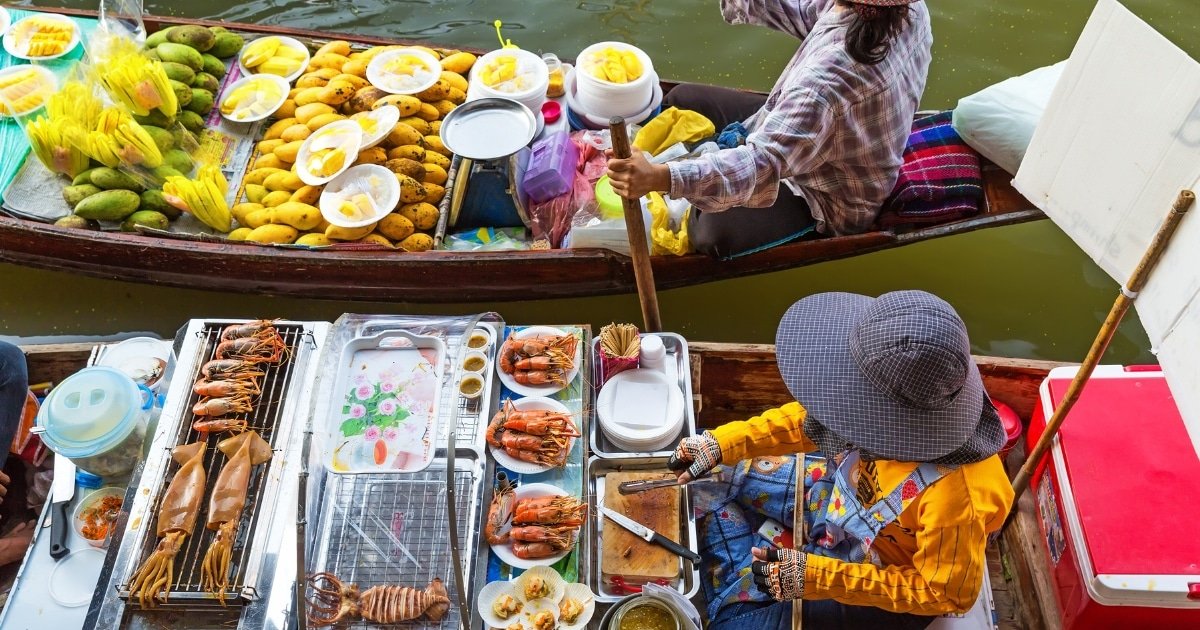 พ่อค้าแม่ค้าสองคนขายมะม่วง ข้าวเหนียว และอาหารทะเลย่างจากเรือที่ ตลาดน้ำใกล้กรุงเทพ ตลาดน้ำใกล้กรุงเทพ) มองจากมุมสูง.