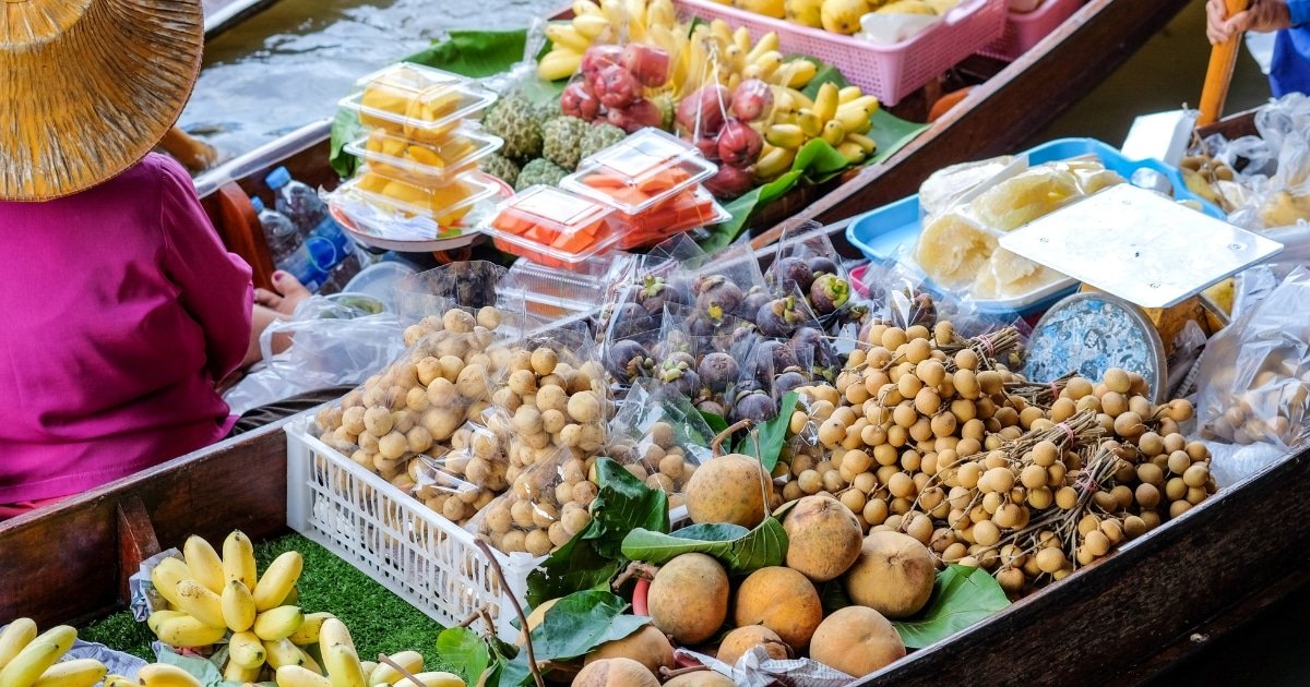 ที่ตลาดน้ำใกล้กรุงเทพฯ มีเรือสองลำที่นำเสนอผลไม้สดและผลิตผลบรรจุหีบห่อ เช่น กล้วย ลำไย และผลไม้เมืองร้อนอื่นๆ ที่ตลาดน้ำลอยน้ำอันคึกคัก.