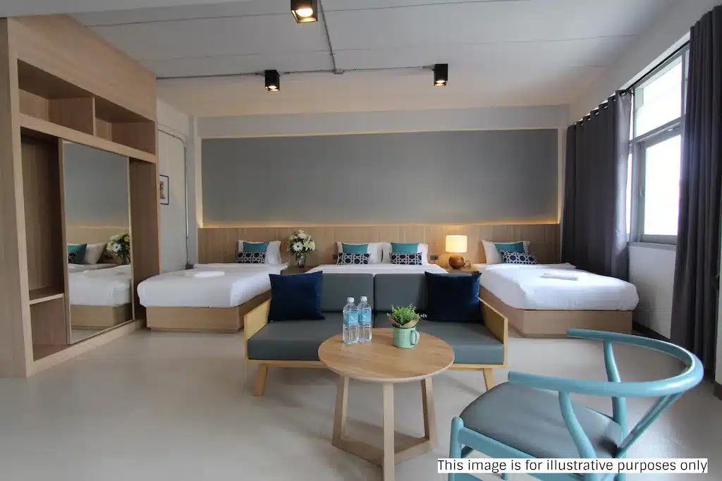 ห้องพักโรงแรมสมัยใหม่พร้อมเตียง ที่เที่ยวสุราษฎร์ธานี คู่สองเตียง โซฟาขนาดเล็ก โต๊ะกลมพร้อมขวดน้ำและต้นไม้ เก้าอี้ หน้าต่างบานใหญ่ และตู้เสื้อผ้าบานกระจก—เหมาะสำหรับการพักผ่อนหลังจากสำรวจสถานที่ท่องเที่ยวในสุราษฎร์ธานี.