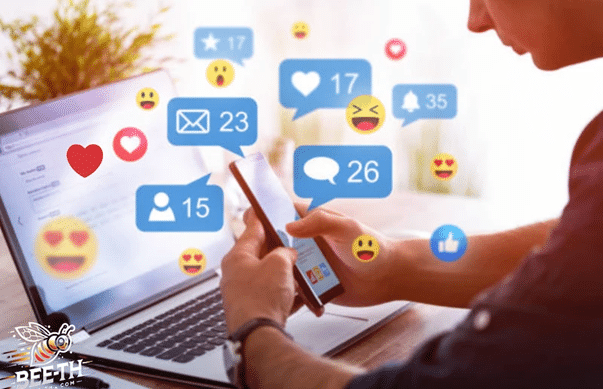 บุคคลหนึ่งกำลังใช้สมาร์ทโฟนใกล้กับแล็ปท็อป โดยมีไอคอนการแจ้งเตือนจากโซเชียลมีเดียสำหรับการกดไลค์ ข้อความ และปฏิกิริยาต่าง ๆ แสดงอยู่บนหน้าจอ ซึ่งบ่งชี้ว่าอาจมีการใช้เว็บไซต์เพิ่มยอดวิวเพื่อกระตุ้นการมีส่วนร่วมออนไลน์.