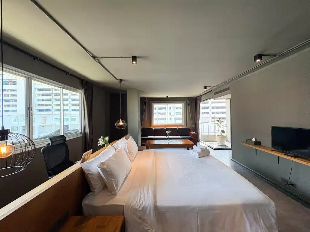 ห้องพักโรงแรมสมัยใหม่ที่ โรงแรมกรุงเทพ ประกอบด้วยเตียงขนาด โรงแรมกรุงเทพ ใหญ่ โต๊ะทำงาน โทรทัศน์ติดผนัง โซฟา และหน้าต่างบานใหญ่ที่มองเห็นวิวเมืองที่สวยงาม—เหมาะสำหรับการเข้าพักครั้งต่อไปของคุณในใจกลางกรุงเทพฯ.