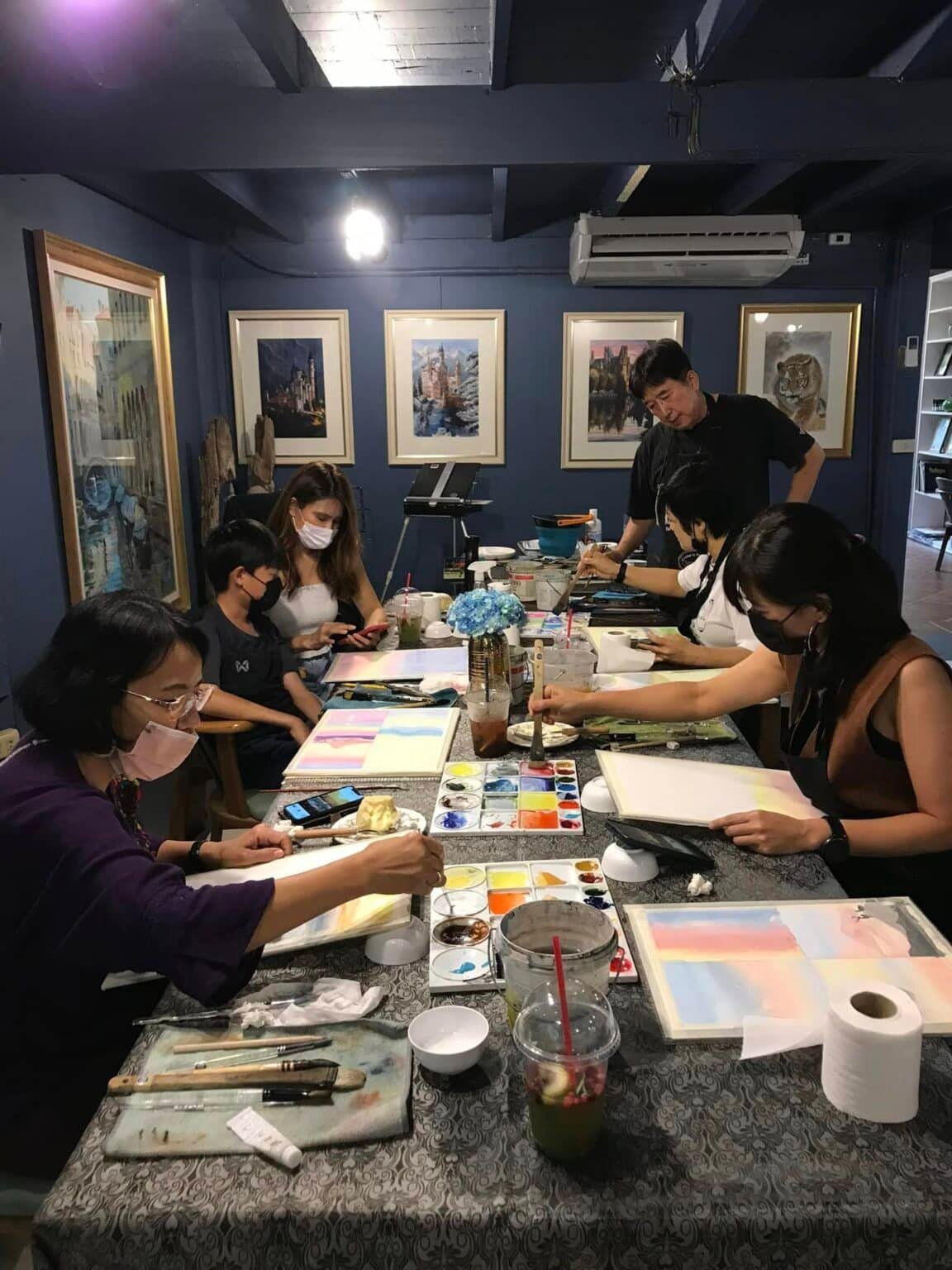 กลุ่มคนกำลังวาดภาพด้วยกัน จับภาพความงดงามของทิวทัศน์ สถานที่ท่องเที่ยวเขาใหญ่ ลงบนผืนผ้าใบของพวกเขา.