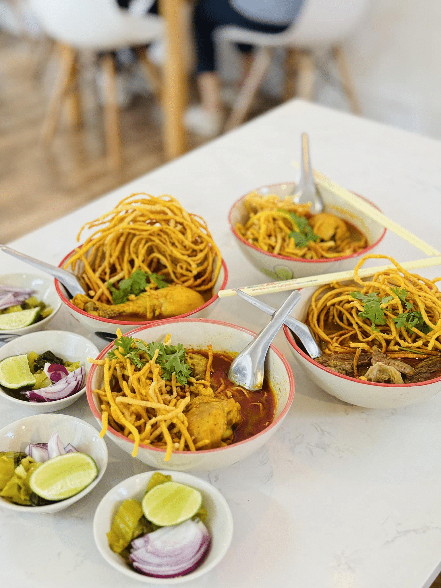 ข้าวซอยสามชาม เสิร์ฟพร้อมเส้นกรอบ ผักชี และไก่ ราดด้วยน้ำซุปเข้มข้น เสิร์ฟพร้อมมะนาว ผักกาดดอง และหอมแดง—เหมาะสำหรับรับประทานหลังจากเที่ยวชมสถานที่ท่องเที่ยวในน่าน.