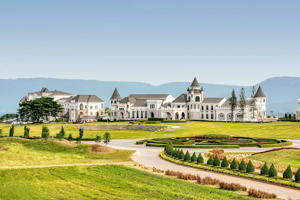 คฤหาสน์ขนาดใหญ่สไตล์ยุโรปสีขาวพร้อมหอคอยและสวนที่ตกแต่งอย่างประณีตนั่งอยู่ท่ามกลางฉากหลังของเนินเขาไกลภายใต้ท้องฟ้าแจ่มใส ทำให้เป็นสถานที่ท่องเที่ยวเขาใหญ่ที่ต้องไปเยือนสำหรับผู้ที่วางแผนจะเที่ยวเขาใหญ่.