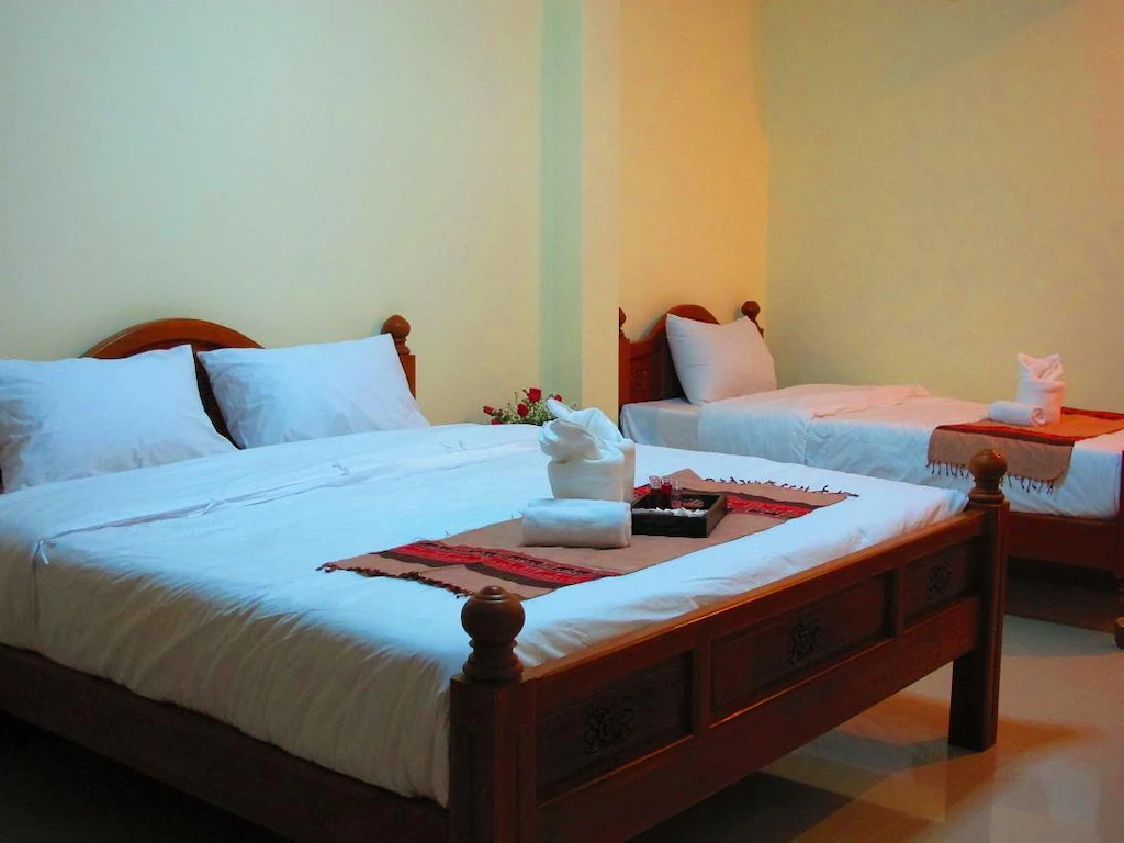 ห้องพักโรงแรมที่ ที่พักบ่อเกลือ พร้อมเตียงไม้สองเตียง แต่ละเตียงปูด้วยผ้าปูที่นอนสีขาวและหมอน ผ้าเช็ดตัวพับวางอยู่บนเตียง และมีชุดเครื่องใช้ในห้องน้ำจัดวางไว้ตรงกลาง.