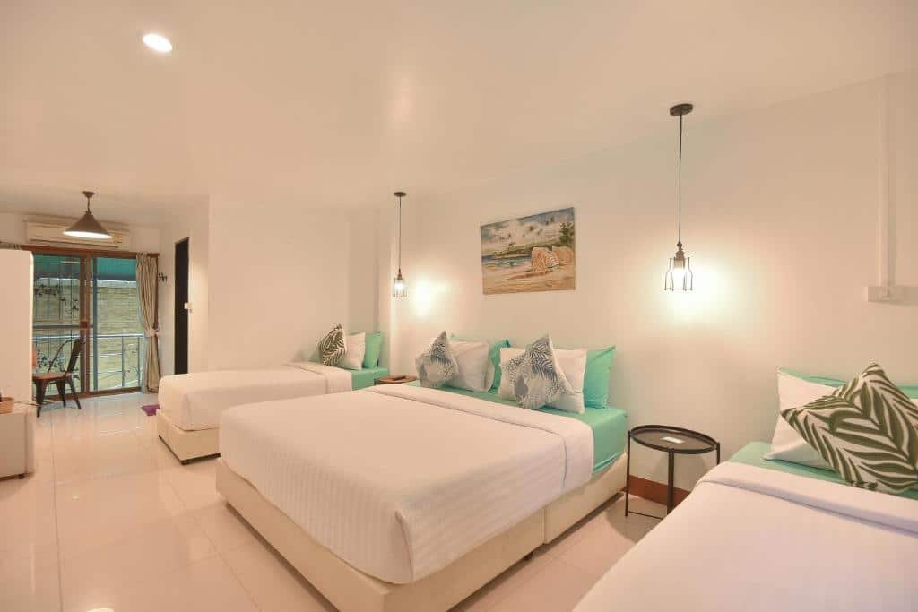 ห้องพักโรงแรมกว้างขวางที่ โรงแรมอยุธยา พร้อมเตียงสามเตียง ผนังสีขาว ผ้าปูที่นอนสีฟ้าอ่อน หมอนประดับ โคมไฟเพดานสไตล์โมเดิร์น และระเบียงที่มองเห็นวิว—เหมาะสำหรับการเข้าพักของคุณในอยุธยา.