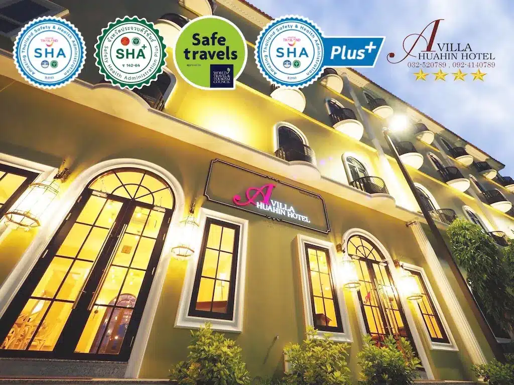 ภายนอกของโรงแรม A Villa Hua Hin (โรงแรมหัวหิน) ในตอนกลางคืน พร้อมป้ายรับรองมาตรฐาน SHA, SHA Plus+ และ Safe Travels แสดงไว้เหนือทางเข้า.