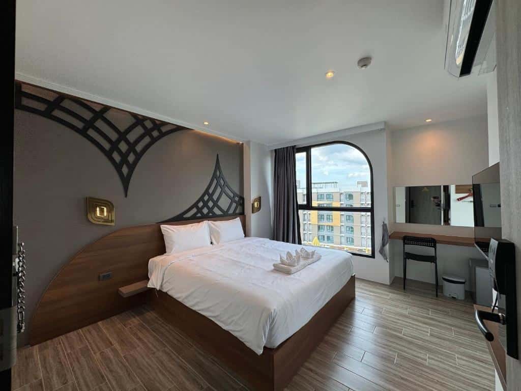 ห้องพักโรงแรมสมัยใหม่ที่ ที่พักอยุธยา ทันสมัย พร้อมเตียงขนาดใหญ่, การออกแบบผนังตกแต่ง, พื้นไม้, โต๊ะทำงาน, กระจก, และหน้าต่างที่มองเห็นวิวเมือง.