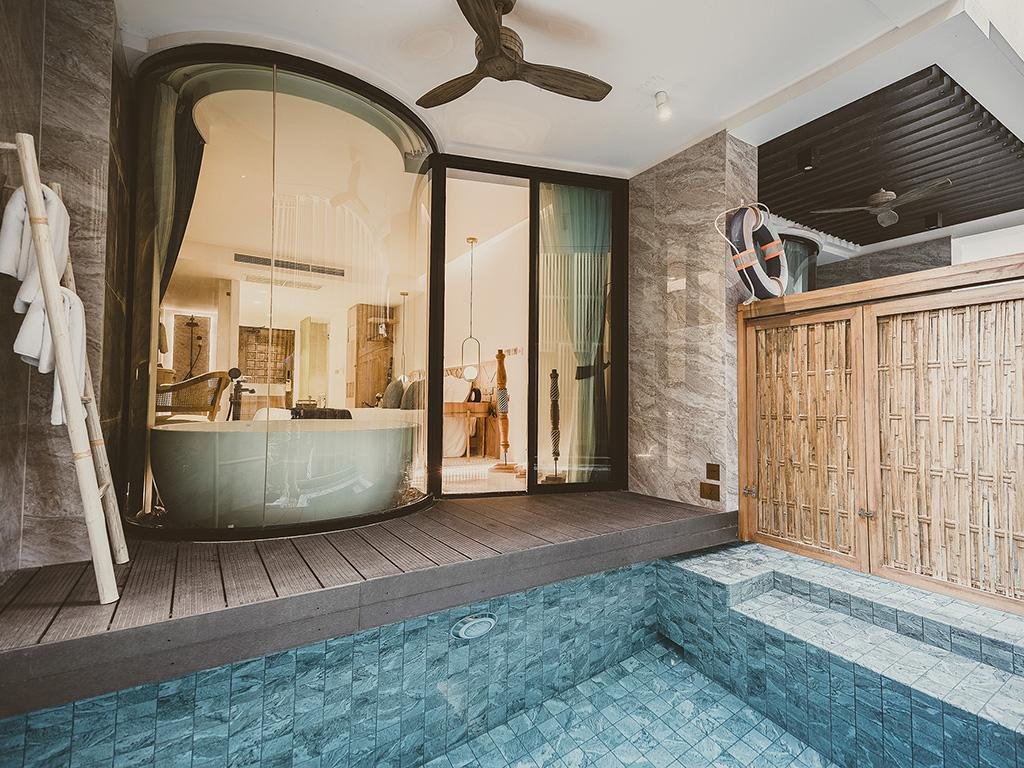 พื้นที่ภายในและภายนอกที่ทันสมัยในสไตล์สถานที่ท่องเที่ยวเชียงใหม่ ประกอบด้วยสระว่ายน้ำกระเบื้องเปล่า ประตูกระจก อ่างอาบน้ำทรงกลม ระเบียงไม้ และฉากบังตาไม้ไผ่.