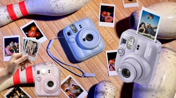 กล้องถ่ายรูปทันที Instax 3 เครื่องและภาพถ่ายทันทีหลายใบถูกจัดวางบนพื้นสนามโบว์ลิ่ง โดยมีพินโบว์ลิ่งและลูกโบว์ลิ่งกระจายอยู่รอบๆ.