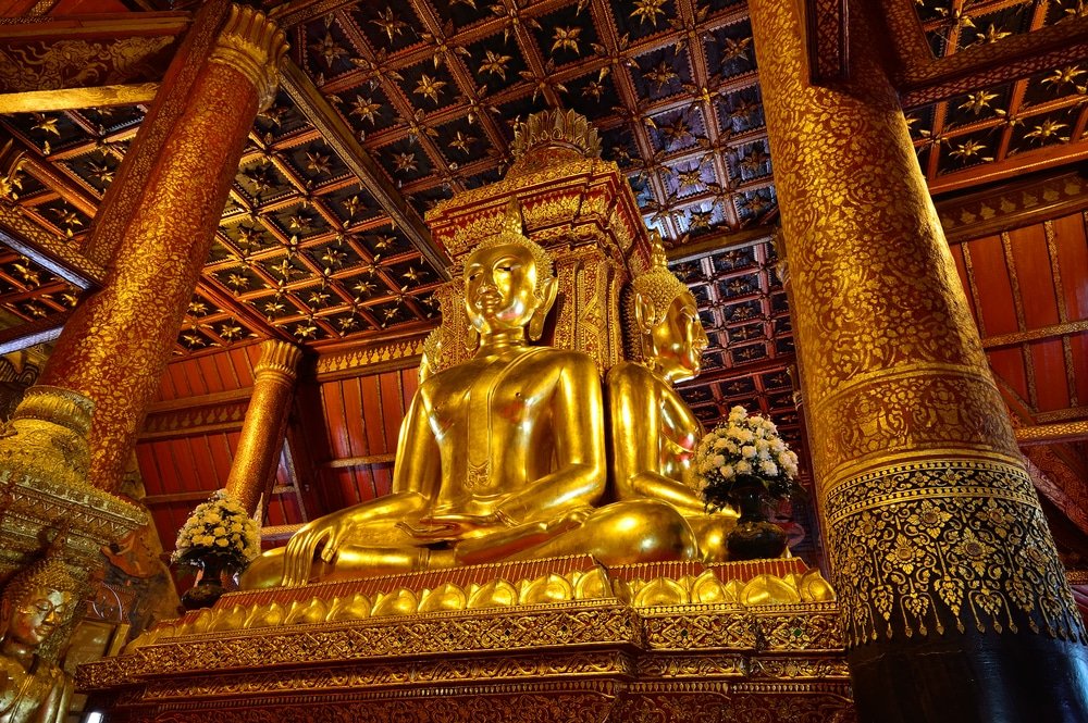 พระพุทธรูปทองขนาดใหญ่ตั้งหันหลังชนกันภายในวัดที่ตกแต่งอย่างวิจิตรบรรจงด้วยลวดลายที่ซับซ้อนและจัดแต่งดอกไม้อย่างประณีต—เป็นสถานที่ที่ไม่ควรพลาดสำหรับใครก็ตามที่ต้องการสัมผัสประสบการณ์การท่องเที่ยวภาคเหนือและมรดกทางวัฒนธรรมอันเป็นเอกลักษณ์ของภาคเหนือ.