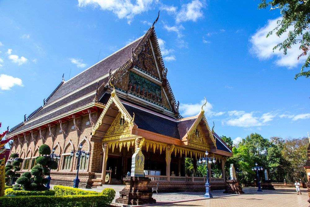 วัดไทยแบบดั้งเดิมที่มีรายละเอียดตกแต่งด้วยทองอย่างวิจิตรบรรจง หลังคาแหลม และรูปปั้นที่ทางเข้า ล้อมรอบด้วยต้นไม้ใต้ท้องฟ้าสีคราม — นี่คือสถานที่ท่องเที่ยวในเที่ยวเชียงคาน ที่ไม่ควรพลาดสำหรับใครก็ตามที่ต้องการสัมผัสความงามทางวัฒนธรรมของภูมิภาคนี้.