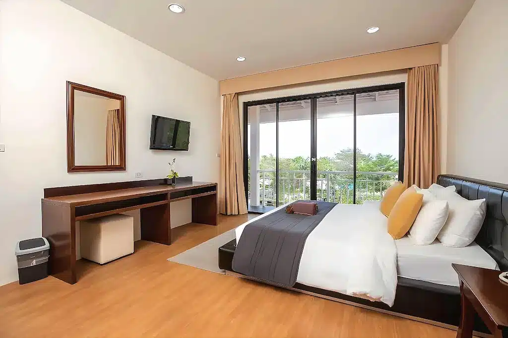 ห้องพักโรงแรมบนเกาะลาร์น ที่มีเตียงควีนไซส์ โต๊ะทำงานไม้ โทรทัศน์ และประตูเลื่อนกระจกที่เปิดออกสู่ระเบียง.