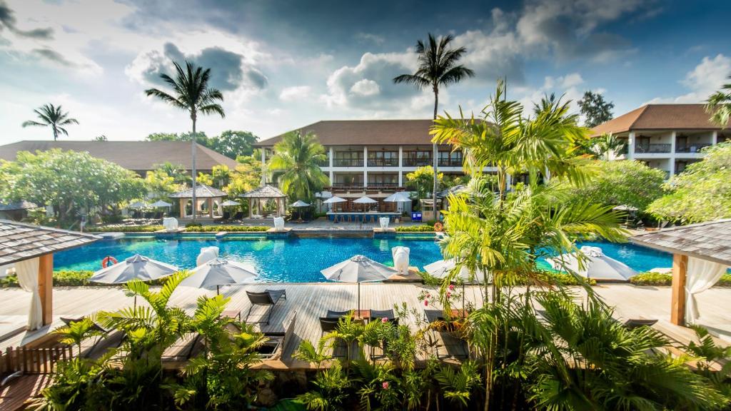 สระว่ายน้ำของรีสอร์ทที่ล้อมรอบด้วยต้นปาล์ม เก้าอี้นอนพร้อมร่ม และอาคารโรงแรมหลายชั้น ที่ที่พักแห่งนี้บนเกาะสมุย.