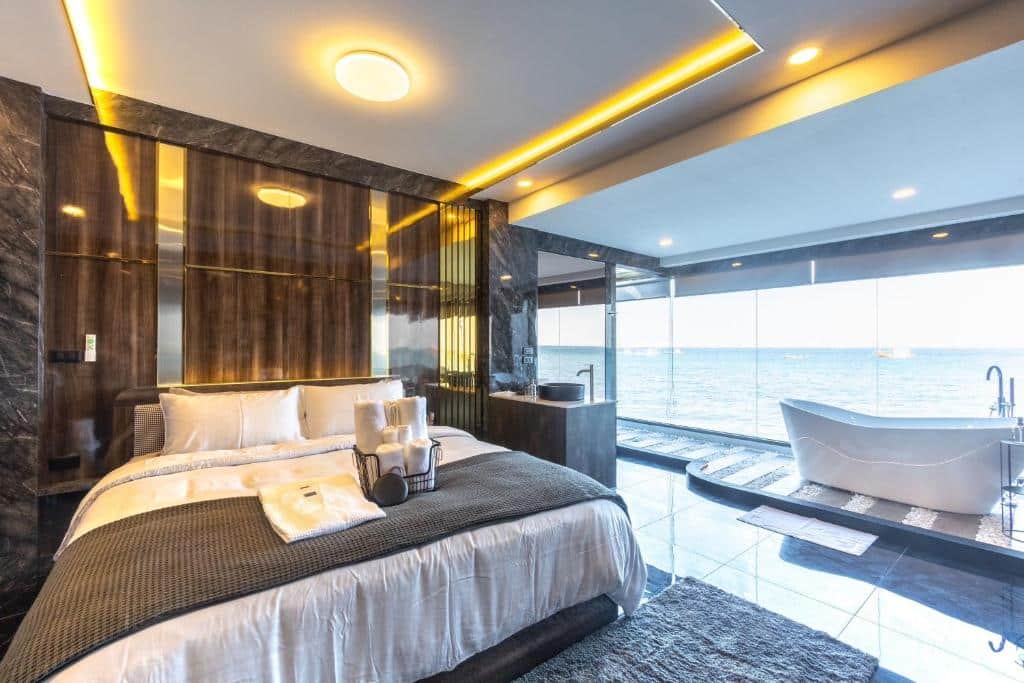ห้องพักโรงแรมสไตล์ทันสมัย ที่มาพร้อมเตียงนอน อ่างอาบน้ำแบบตั้งอิสระ และวิวทะเลที่มองเห็นได้ผ่านหน้าต่างสูงจากพื้นถึงเพดาน ที่ที่พักริมชายหาดบนเกาะลันแห่งนี้.
