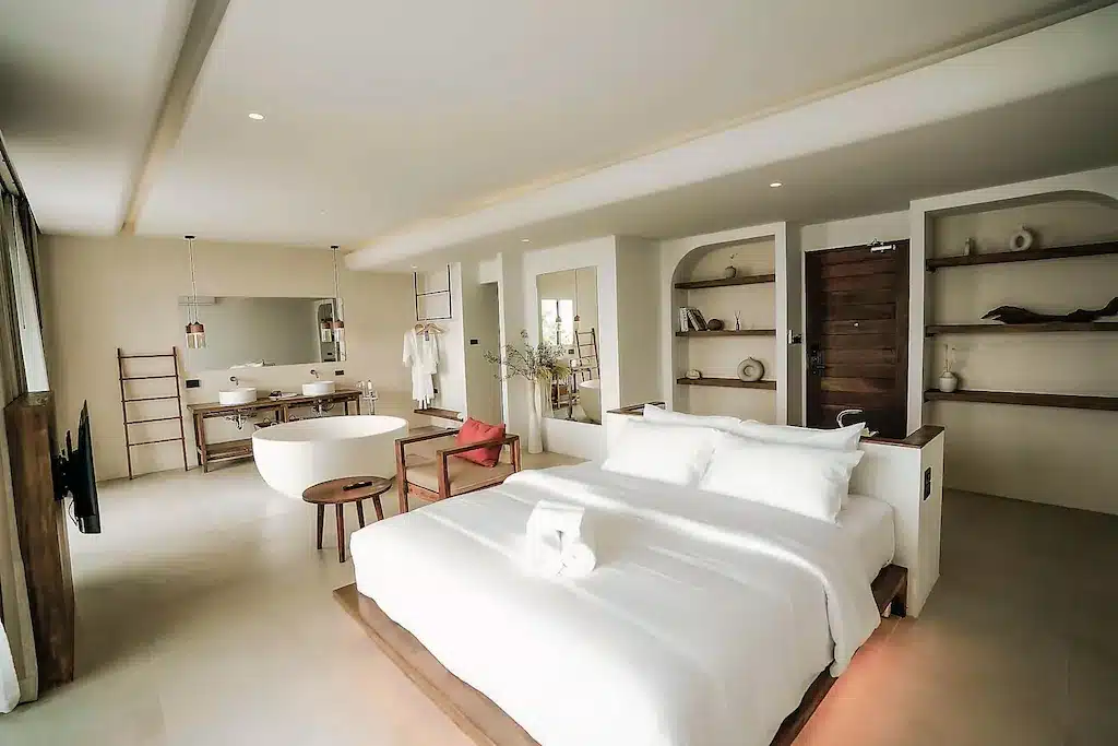 ห้องพักในโรงแรมแห่งนี้มีเตียงควีน อ่างอาบน้ำสีขาว และชั้นวางของแบบเปิด ที่พักราคาประหยัดบนเกาะลันนี้.