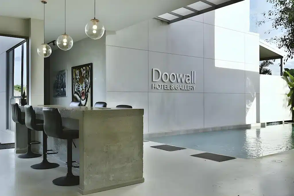 แท่งคอนกรีตพร้อมเก้าอี้สีดำตั้งอยู่ข้างสระว่ายน้ำที่ Doowall HOTEL & GALLERY ซึ่งเป็นสถานที่ยอดนิยมสำหรับนักท่องเที่ยวในเชียงราย.