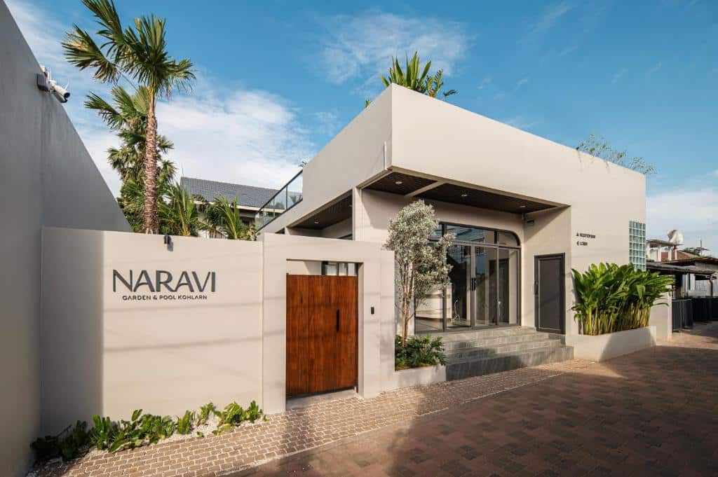 ด้านนอกของ Naravi Garden & Pool Kohlarn ซึ่งมีอาคารสีเบจพร้อมประตูไม้และป้ายแสดงชื่อโรงแรม เป็นตัวเลือกยอดนิยมสำหรับที่พักราคาประหยัดบนเกาะลาร์น.