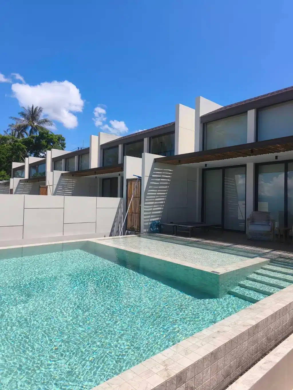 แถววิลลาสมัยใหม่ที่มีสระว่ายน้ำร่วมกัน ณ รีสอร์ทบนเกาะสมุย ในส่วนเบื้องหน้า.
